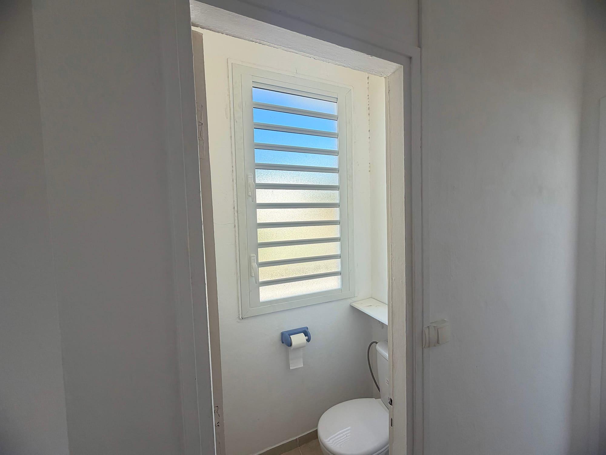 Fenêtre à jalousies aluminium dans des toilettes