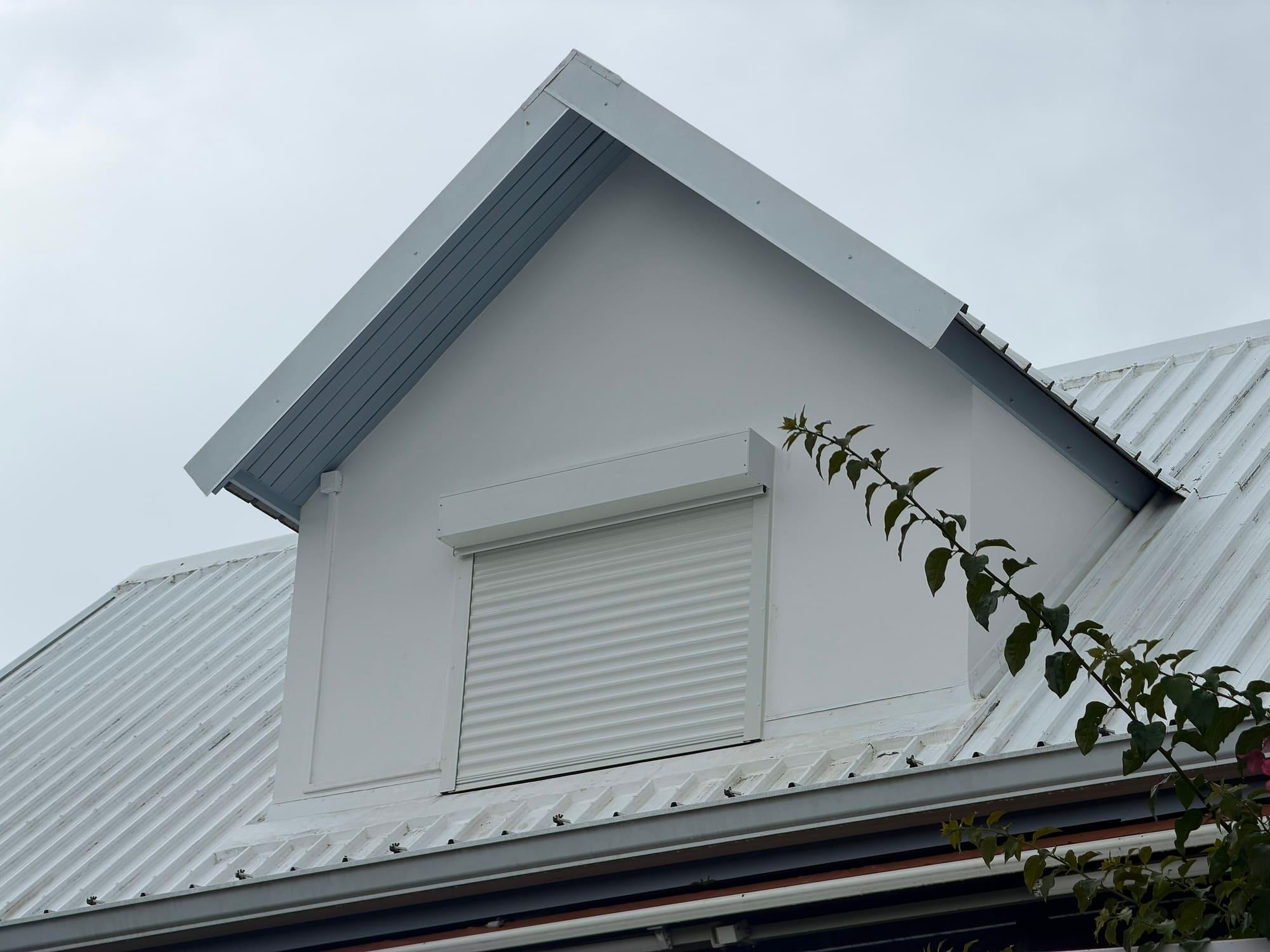 Lucarne de toiture avec volet roulant aluminium au milieu de la végétation